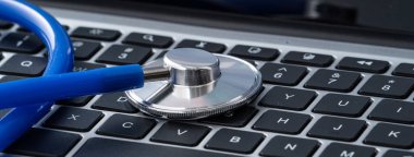 Doktor tasarım konseptini teşhis etti - beyaz çalışma masasındaki bilgisayar klavyesinde stetoskop.