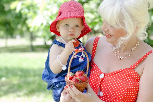 Grandmother and granddaughter are eating strawberries — Stock Photo, Image