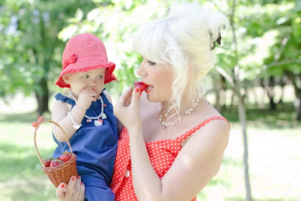 Grandmother and granddaughter are eating strawberries — Stock Photo, Image