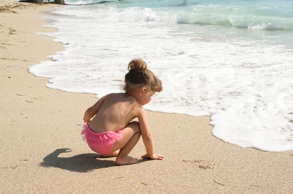 Bebê menina está se divertindo na praia — Fotografia de Stock