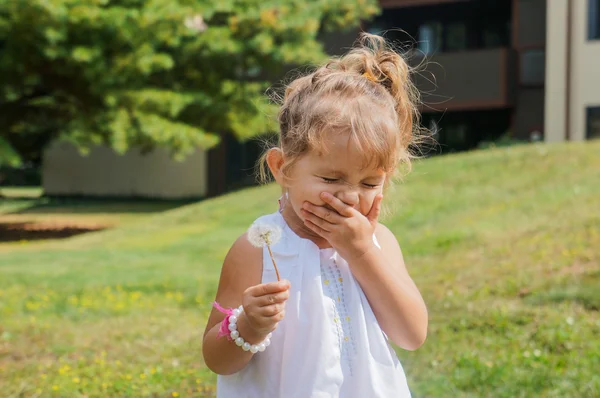 Cute baby girl is blowing a dandelion — Stock Photo, Image