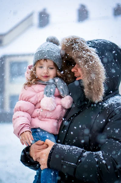 Pai e filha enhoying neve soprando durante o dia — Fotografia de Stock
