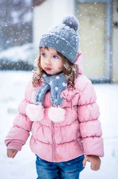 Söt baby flicka i rosa jackan och grå hatt njuter första snö b — Stockfoto