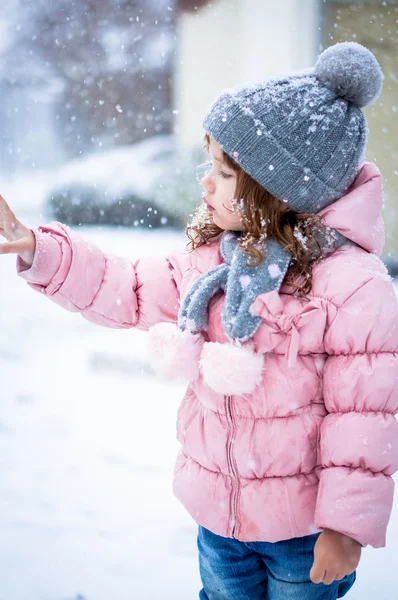 Söt baby flicka i rosa jackan och grå hatt njuter första snö b — Stockfoto