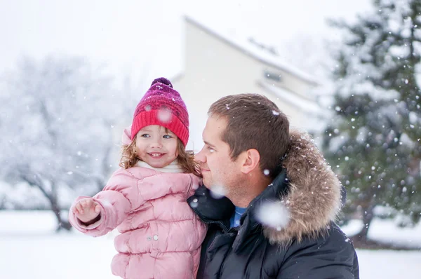 Pai e filha enhoying neve soprando durante o dia — Fotografia de Stock