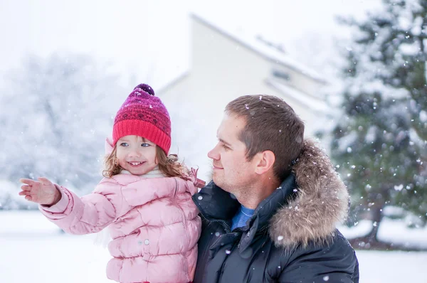 Pai e filha enhoying neve soprando durante o dia — Fotografia de Stock