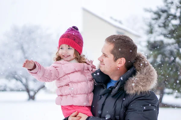 Батько і дочка, що дме снігом вдень — стокове фото