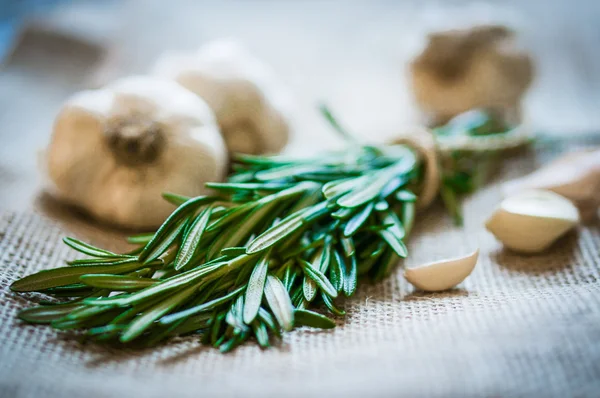 Fresh rosemary with fresh garlic on wooden background — Stock Photo, Image