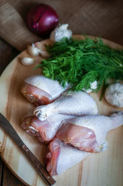 Fresh raw chicken legs on kitchen cutting board with dill and garlic — Stock Photo, Image