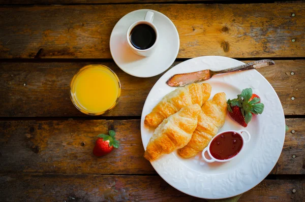 Croissants pretos com café preto no fundo de madeira — Fotografia de Stock