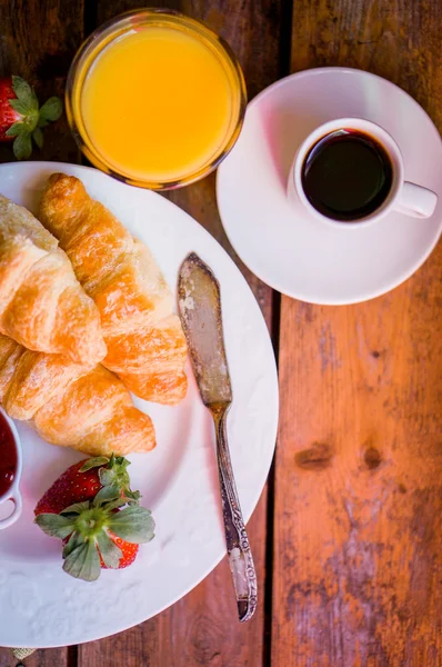 Croissants pretos com café preto no fundo de madeira — Fotografia de Stock