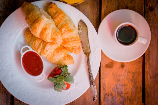 Croissants pretos com café preto no fundo de madeira — Fotografia de Stock