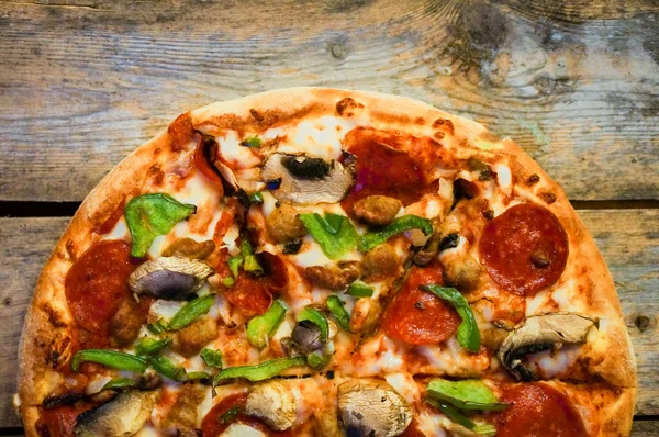 Pizza de pepperoni casera en rodajas sobre fondo rústico de madera — Foto de Stock
