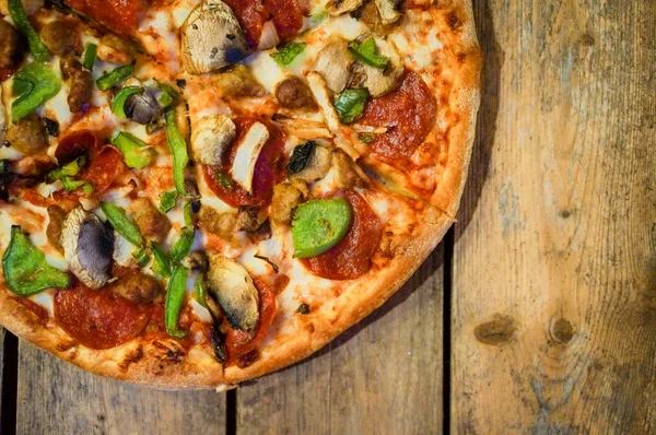 Sliced home made pepperoni pizza on wooden rustic background — Stock Photo, Image