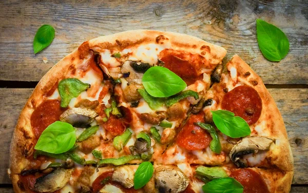 Sliced home made pepperoni pizza on wooden rustic background — Stock Photo, Image