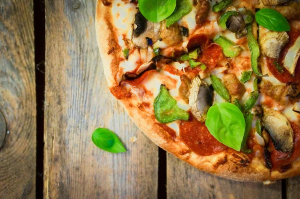 Sliced home made pepperoni pizza on wooden rustic background — Stock Photo, Image