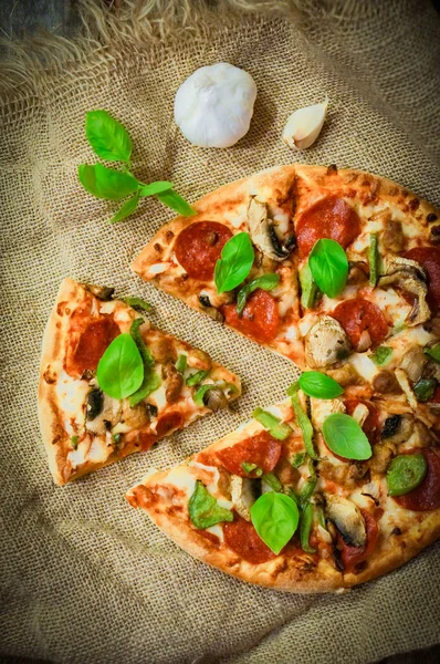 Sliced home made pepperoni pizza on wooden rustic background — Stock Photo, Image