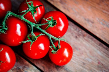 Sarmaşıktaki domatesler ahşap arka planda