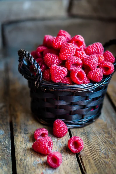 Raspberries in a basket on rustic wooden background — Stock Photo, Image