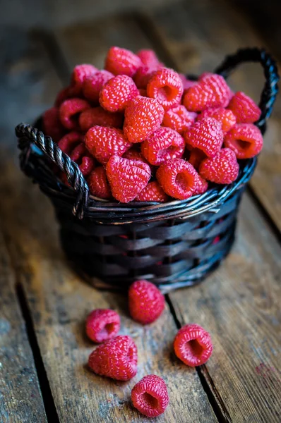 Raspberries in a basket on rustic wooden background — Stock Photo, Image