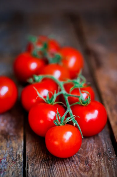 Tomates en la vid sobre fondo rústico de madera — Foto de Stock