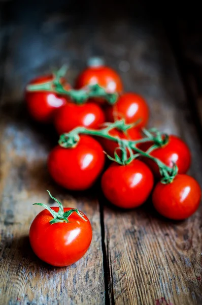 Tomates en la vid sobre fondo rústico de madera — Foto de Stock