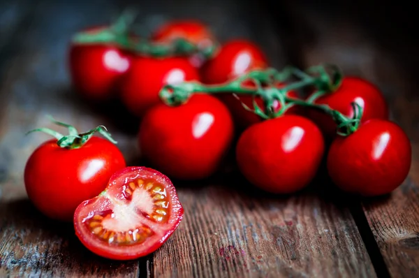 Tomates en la vid sobre fondo rústico de madera — Foto de Stock