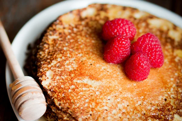 Pannenkoeken met maple siroop en frambozen op houten achtergrond — Stockfoto