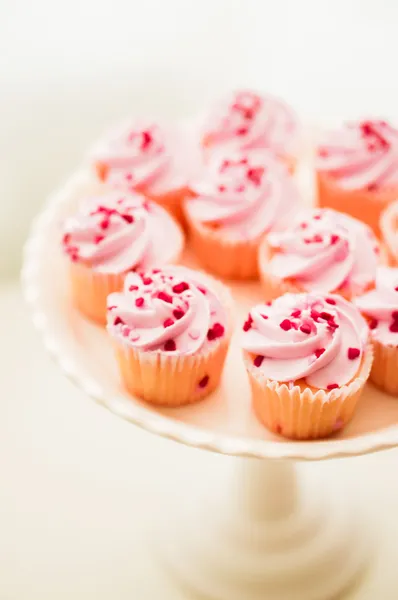 Cupcakes con crema rosa y chispas de corazón — Foto de Stock
