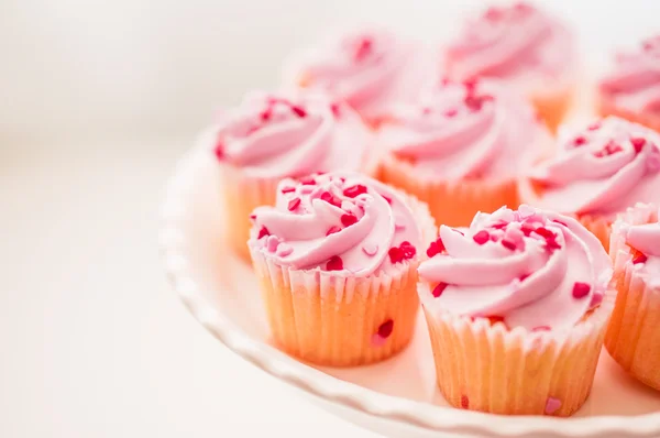 Cupcakes con crema rosa y chispas de corazón — Foto de Stock