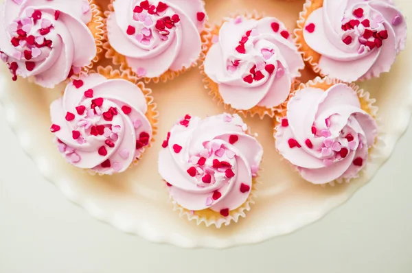 Cupcakes con crema rosa y chispas de corazón — Foto de Stock