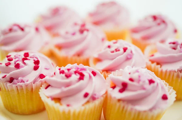 Cupcakes con crema rosa y chispas de corazón — Foto de Stock