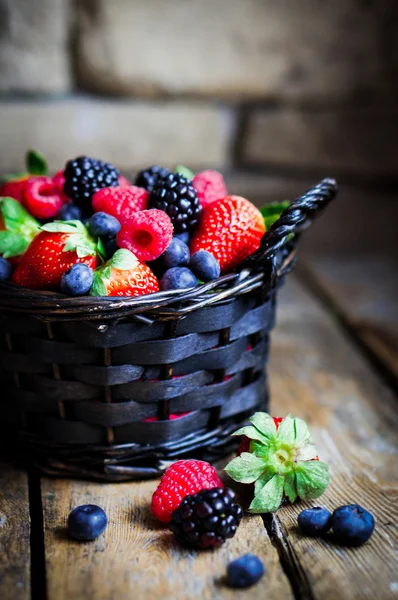 Mix of fresh berries in a basket on rustic wooden background — Stock Photo, Image