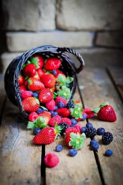 Mischung aus frischen Beeren in einem Korb auf rustikalem Holzgrund — Stockfoto