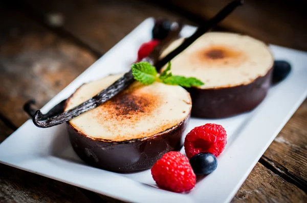 Brulee alla crema con bastoncini di vaniglia e bacche su fondo di legno — Foto Stock