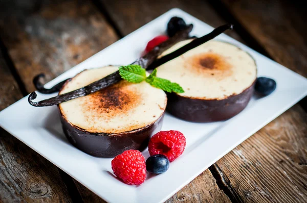 Brulee alla crema con bastoncini di vaniglia e bacche su fondo di legno — Foto Stock