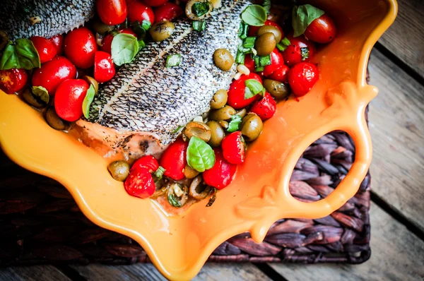 Baked seabass with tomatoes and basil on rustic wooden background — Stock Photo, Image