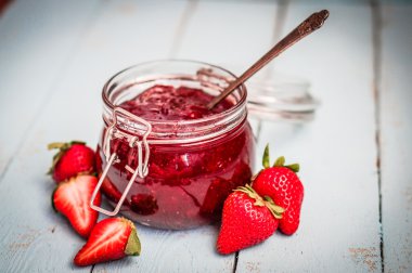 Ahşap arka planda bir kavanozda çilek reçeli