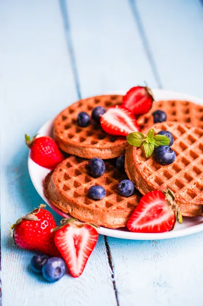 Whole grain waffles with berries on blue wooden background — Stock Photo, Image