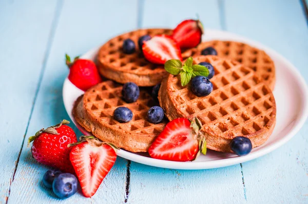 Waffles de grãos inteiros com bagas em fundo de madeira azul — Fotografia de Stock