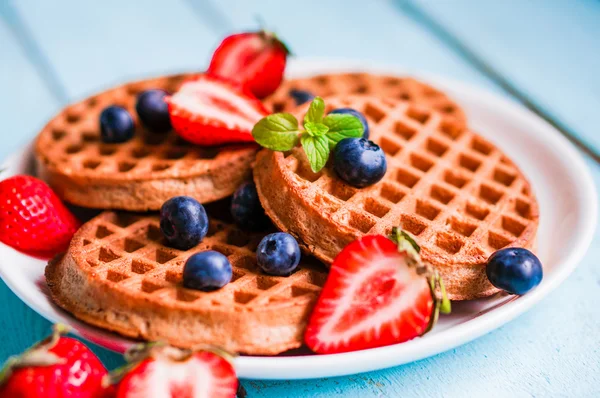 Waffles de grãos inteiros com bagas em fundo de madeira azul — Fotografia de Stock