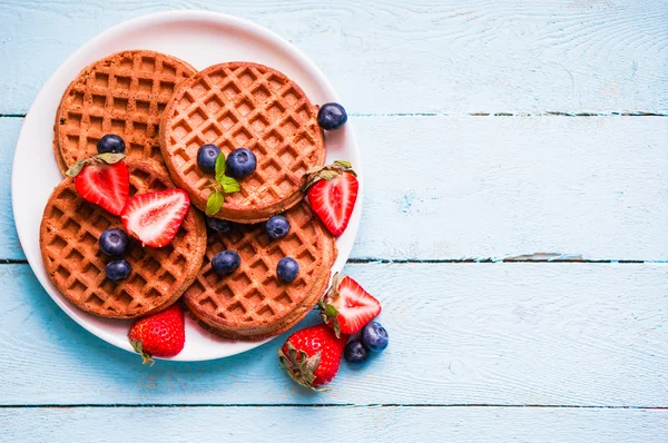 Waffles de grãos inteiros com bagas em fundo de madeira azul — Fotografia de Stock