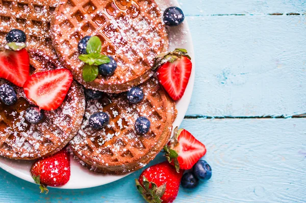 Whole grain waffles with berries on blue wooden background — Stock Photo, Image