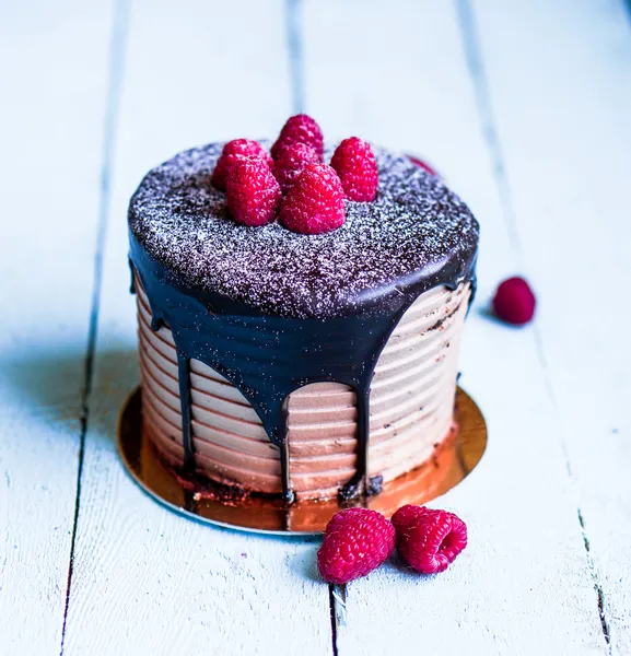 Čokoládový dort s malinami na dřevěné pozadí — Stock fotografie