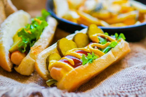 Hot Dogs with french fries in the skillet on wooden background — Stock Photo, Image