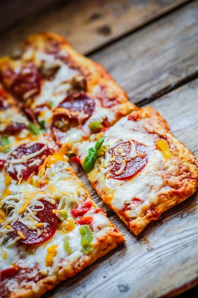 Kwadrat pepperoni pizza na rustykalne drewniane tła — Zdjęcie stockowe