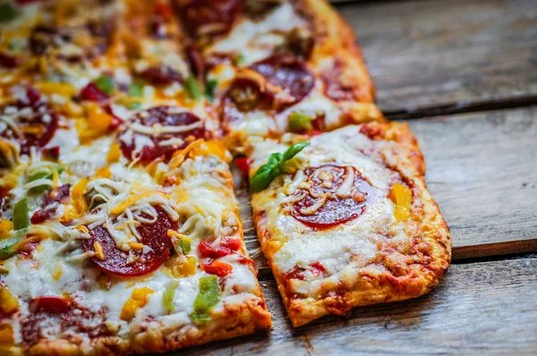 Square pepperoni pizza on rustic wooden background — Stock Photo, Image