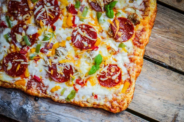 Square pepperoni pizza on rustic wooden background — Stock Photo, Image