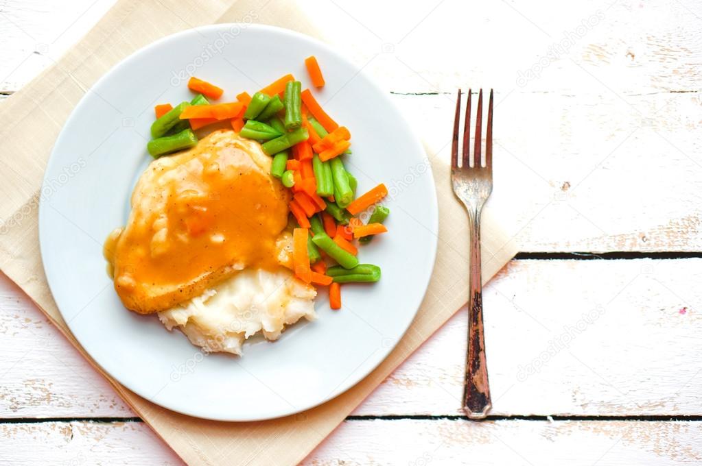 Oven baked chicken in gravy with mashed potatoes and vegetables