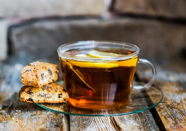 Xícara de chá com limão e biscoitos no fundo de madeira rústica — Fotografia de Stock